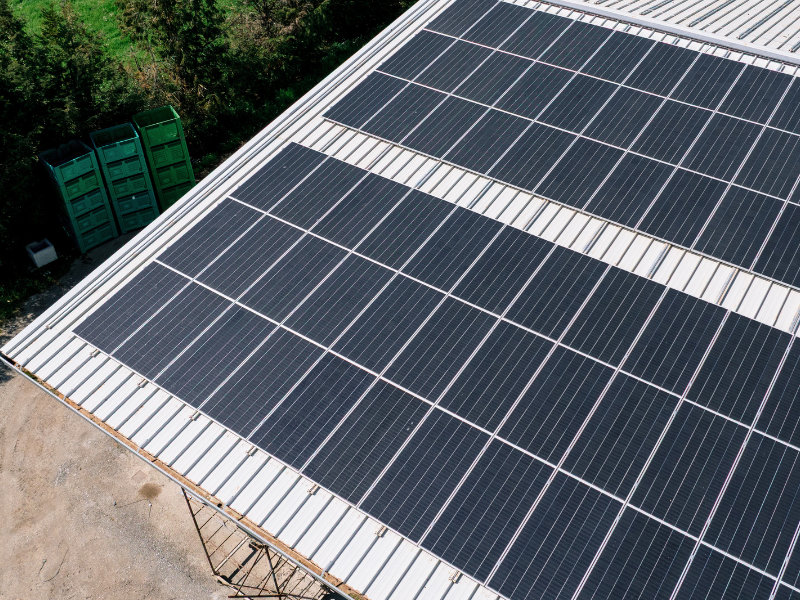 Veduta aerea di un impianto fotovoltaico commerciale installato su un tetto in lamiera grecata, con pannelli solari SunPower Performance disposti in file parallele.