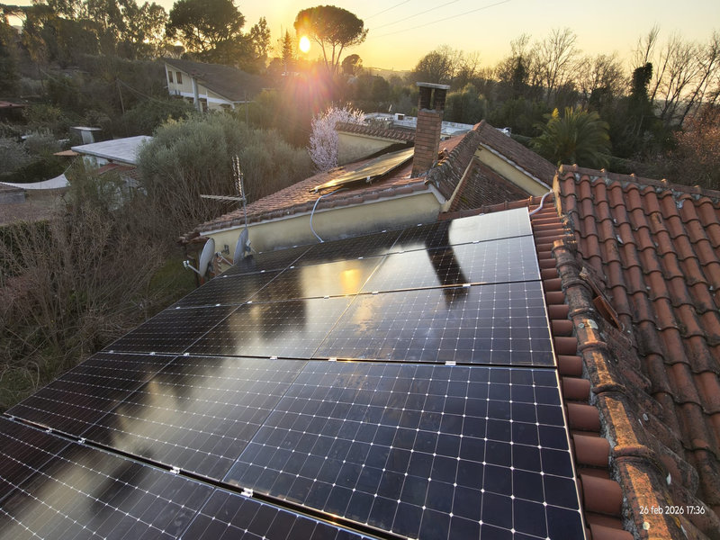 Installazione di impianto fotovoltaico su tetto con coppi tradizionali. Visuale dall'alto al tamonto.